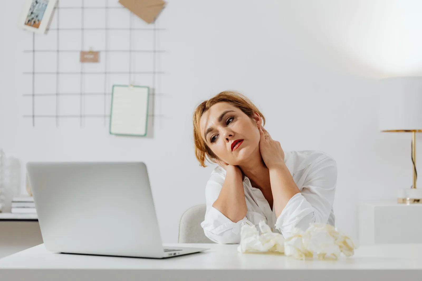 A person at a desk holding a stiff neck